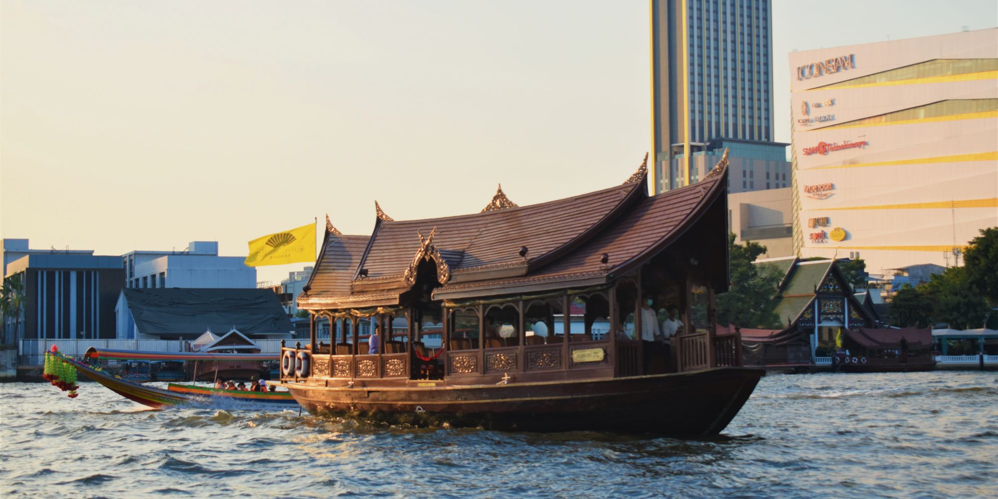 Barca tradicional tailandesa en el río Chao Phraya con el perfil de Bangkok al atardecer
